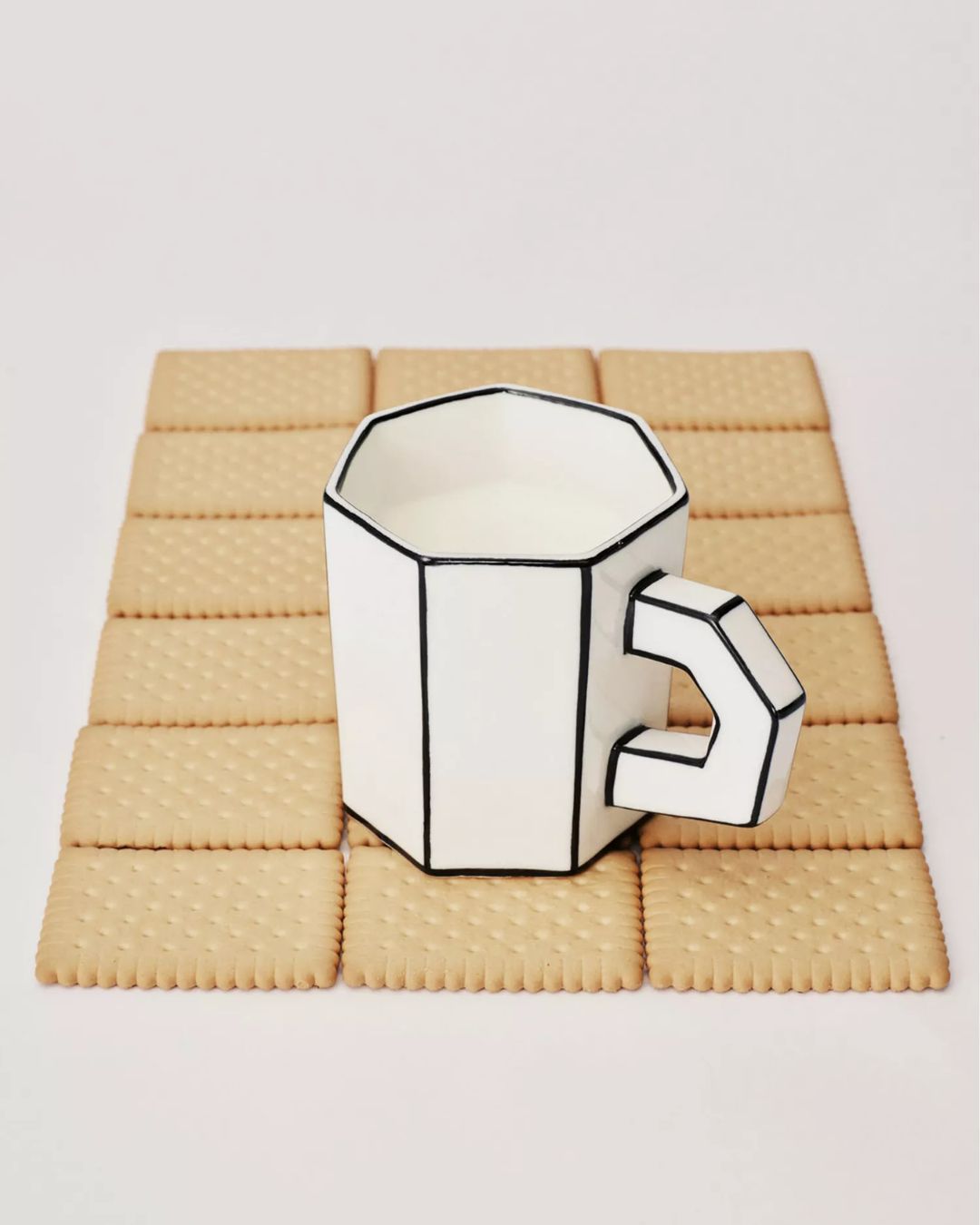 Annebet Philips Carte Blanche Porcelain Tea Cup, set atop a series of digestive biscuits.