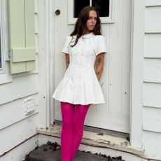 A woman wearing a white dress and hot pink leggings 