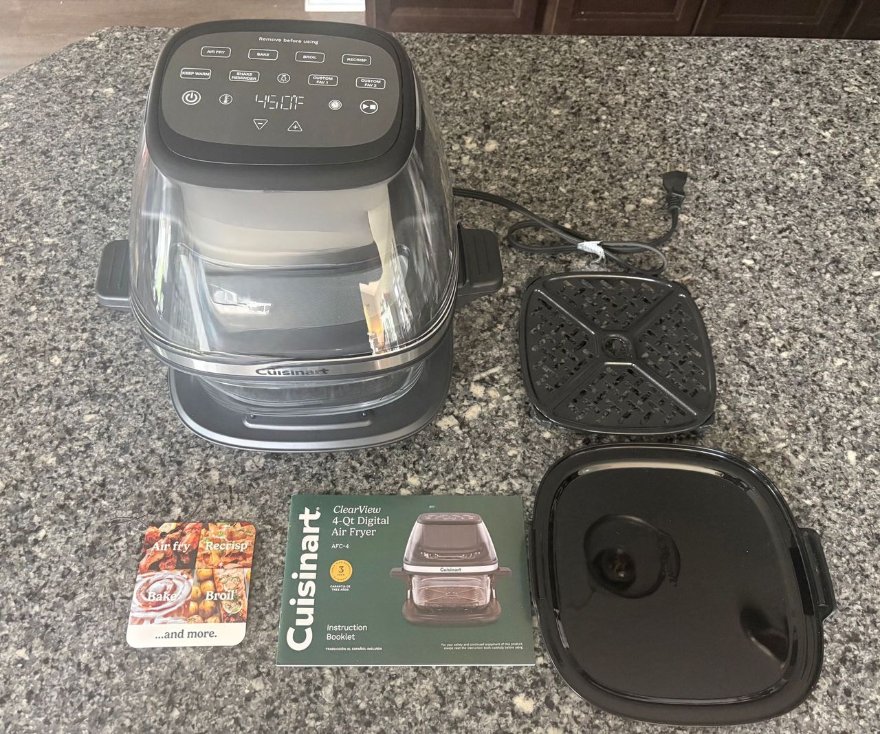 The Cuisinart glass air fryer, laid out with the accessories and manual on a granite countertop