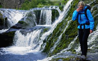 waterproof versus water-resistant: hiker by waterfall