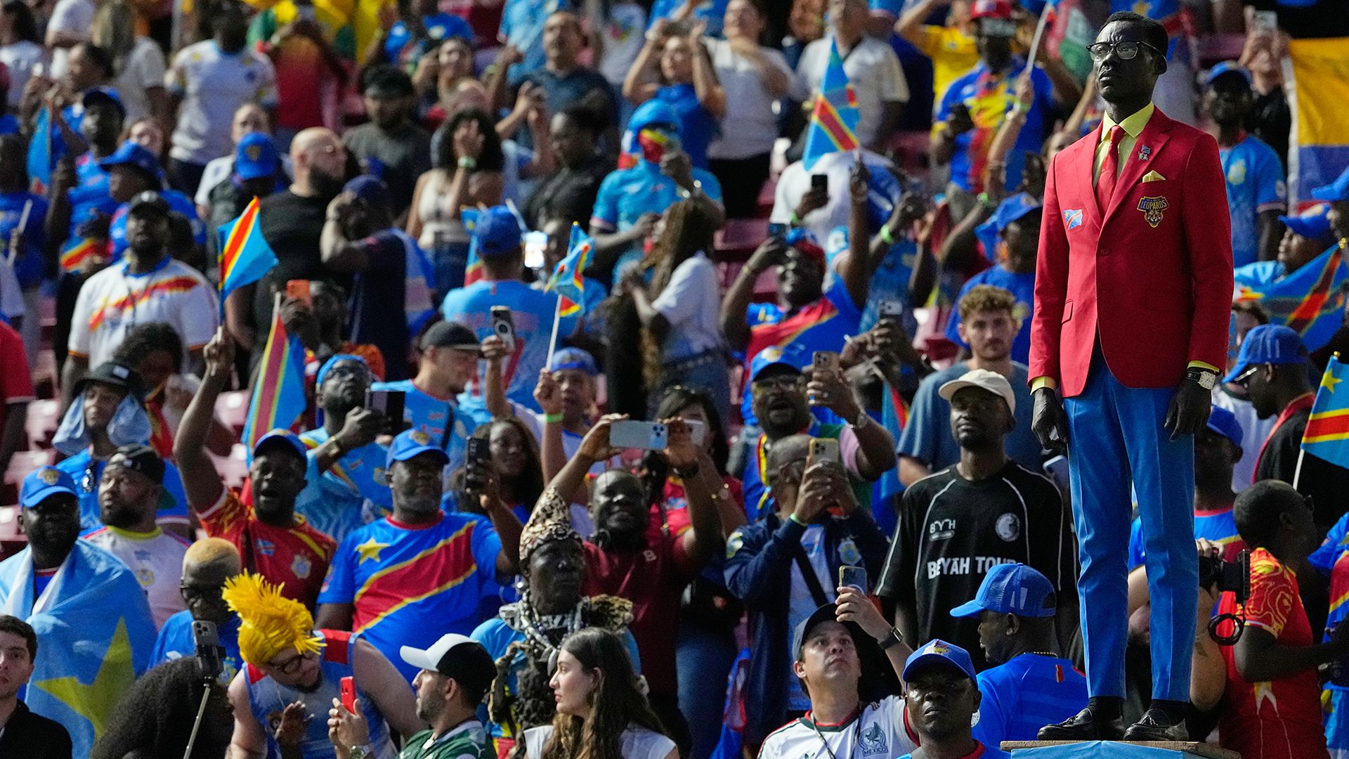 
                                Democratic Republic of Congo supporter Michel Nkuka Mboladinga poses as a statue of Congolese independence hero Patrice Lumumba ahead of the FIFA World Cup match between Colombia and DR Congo in Zapopan, Mexico
                            