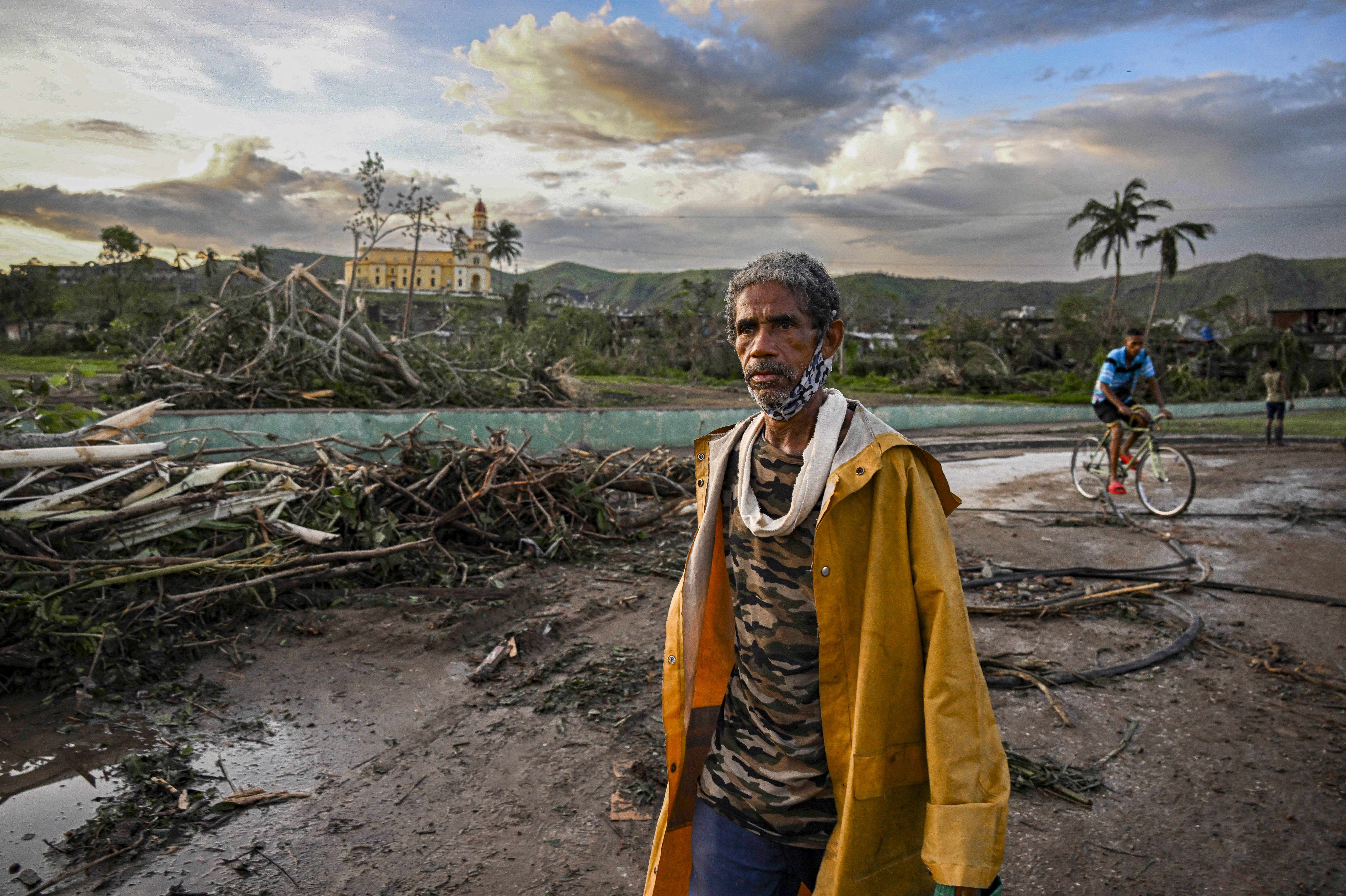 A resident of El Cobre, in the province of Santiago de Cuba, walks past downed trees, power lines and destroyed houses following the passage of Hurricane Melissa, on October 29, 2025. Hurricane Melissa was moving towards Bermuda on Thursday after ripping a path of destruction through the Caribbean that left at least 20 people dead in Haiti, and parts of Jamaica and Cuba in ruins.