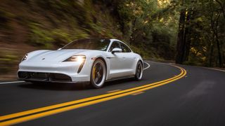 The Porsche Taycan Turbo S driving on a road through a forest