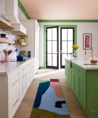 modern kitchen with pale pink ceiling, bright green trim and kitchen island with colorful rug