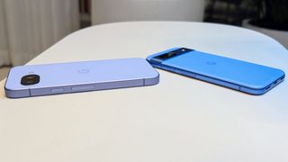 The Iris Google Pixel 9a (left) and Bay Google Pixel 8a (right) aside one another on a white table, the angle showing their relative difference in thickness.