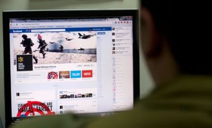 An Israeli solder looks at the Facebook page of the Israeli Defense Forces on Nov. 15: Social media has become a virtual battleground in Israel's Hamas offensive.