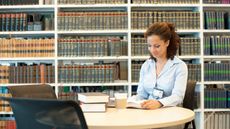 Young female attorney reading at desk in law library