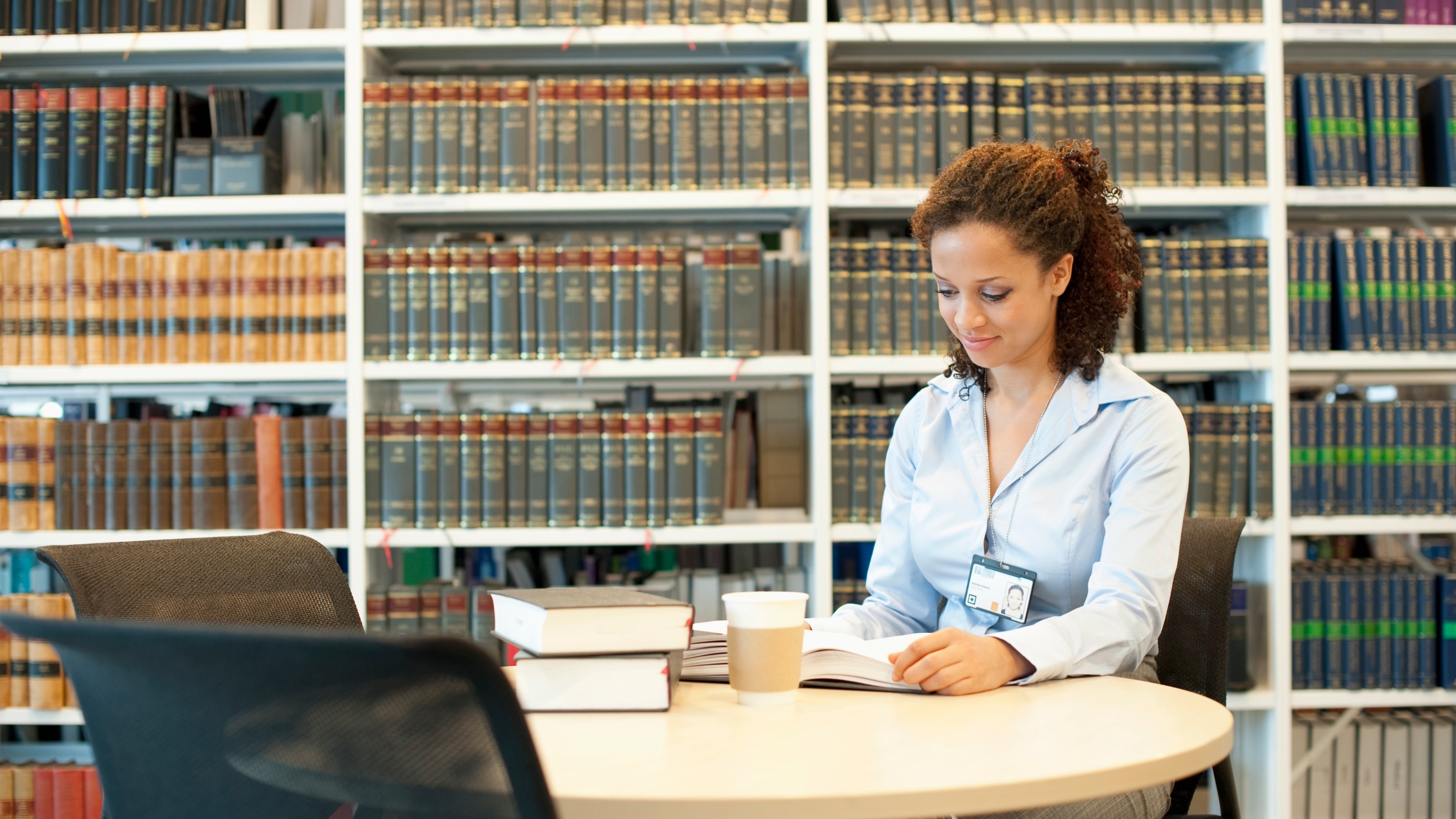Young female attorney reading at desk in law library
