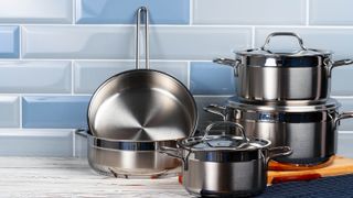 A selection of pots and pans on a kitchen cabinet against a blue wall
