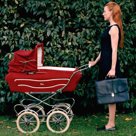 Woman in business attire pushing a pram.