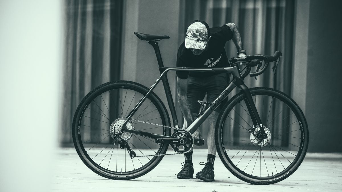 Cyclist holds a Basso Palta gravel bike whilst adjusting the pedals