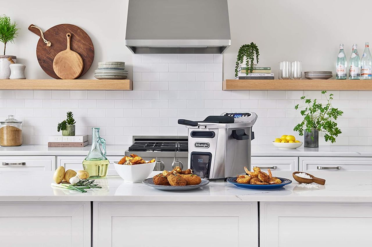 Stock image of on of our best deep fryer on white kitchen island with plates of fried chicken, turkey, vegetables and potatoes