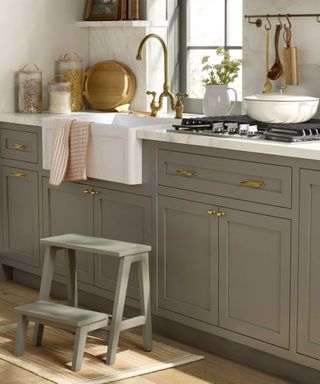 Sage green kitchen cabinets with sage green stool and ceramic sink