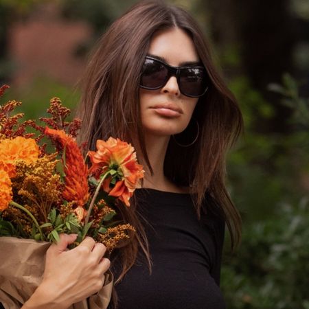 Emily ratajkowski wears oversized sunglasses and a black top.