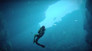 Third person shot of deep-sea diving in a cave in Under the Waves