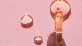 A dropper of sodium hyaluronate serum on a pink background