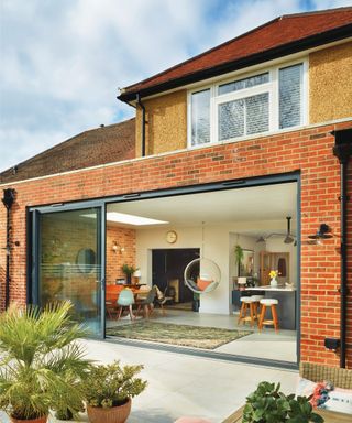 brick and glass flat roof extension on rear of house with doors open