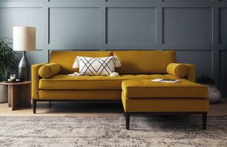 A chaise sofa with yellow upholstery in front of a navy panelled wall