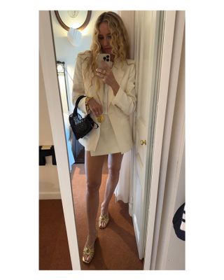 Woman wearing white linen blazer and skirt.