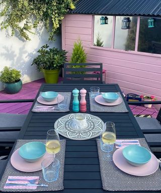 Pastel purple deck ideas with teal and pink table accessories on dark grey wooden garden table