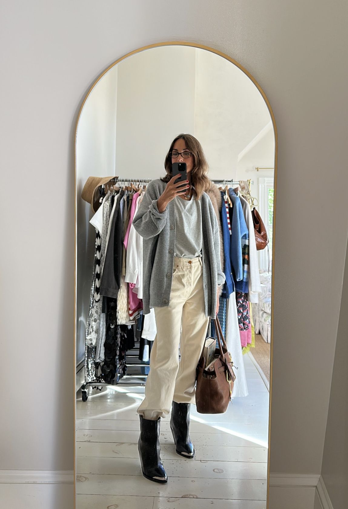 Larissa Mills wearing white jeans, a gray tee, a gray sweater, and black boots