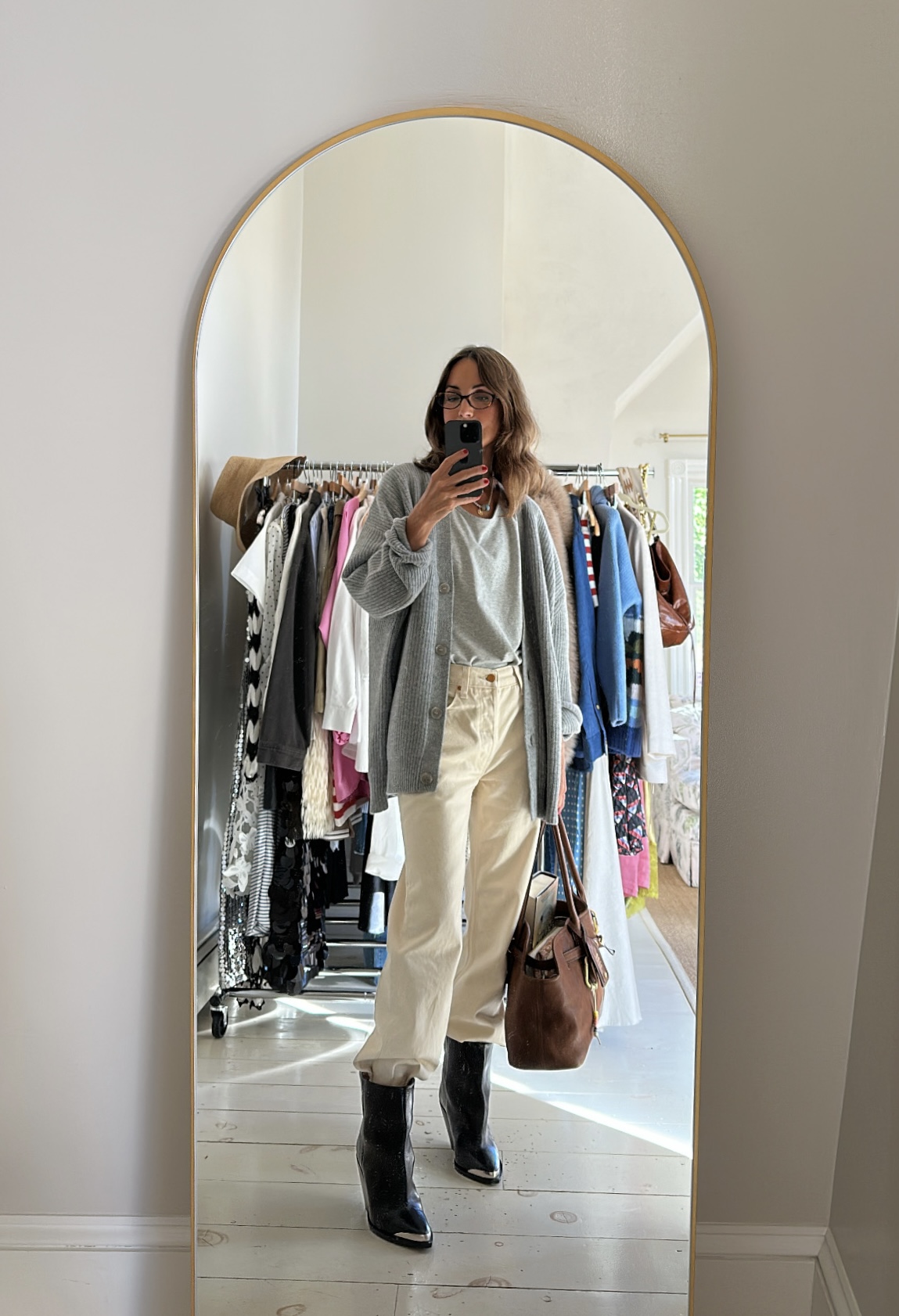 Larissa Mills wearing white jeans, a gray tee, a gray sweater, and black boots