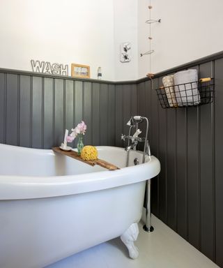 Bathroom with dark painted wall panelling, freestanding bath and white walls