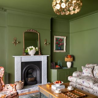 A colour-drenched green living room with a floral-print sofa and chairs