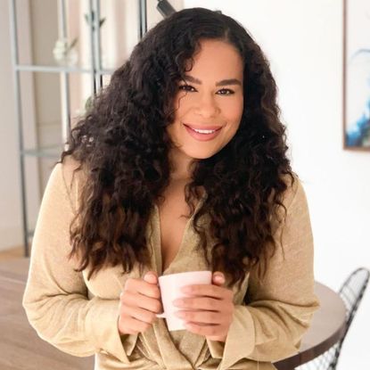 picture of Amerley Ollennu with curly hair smiling and holding a cup of tea