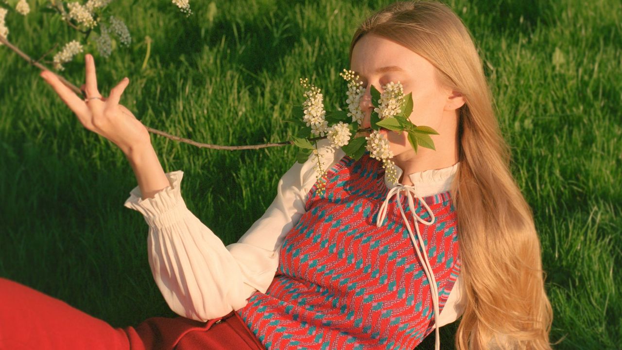 Model in field smelling flowers