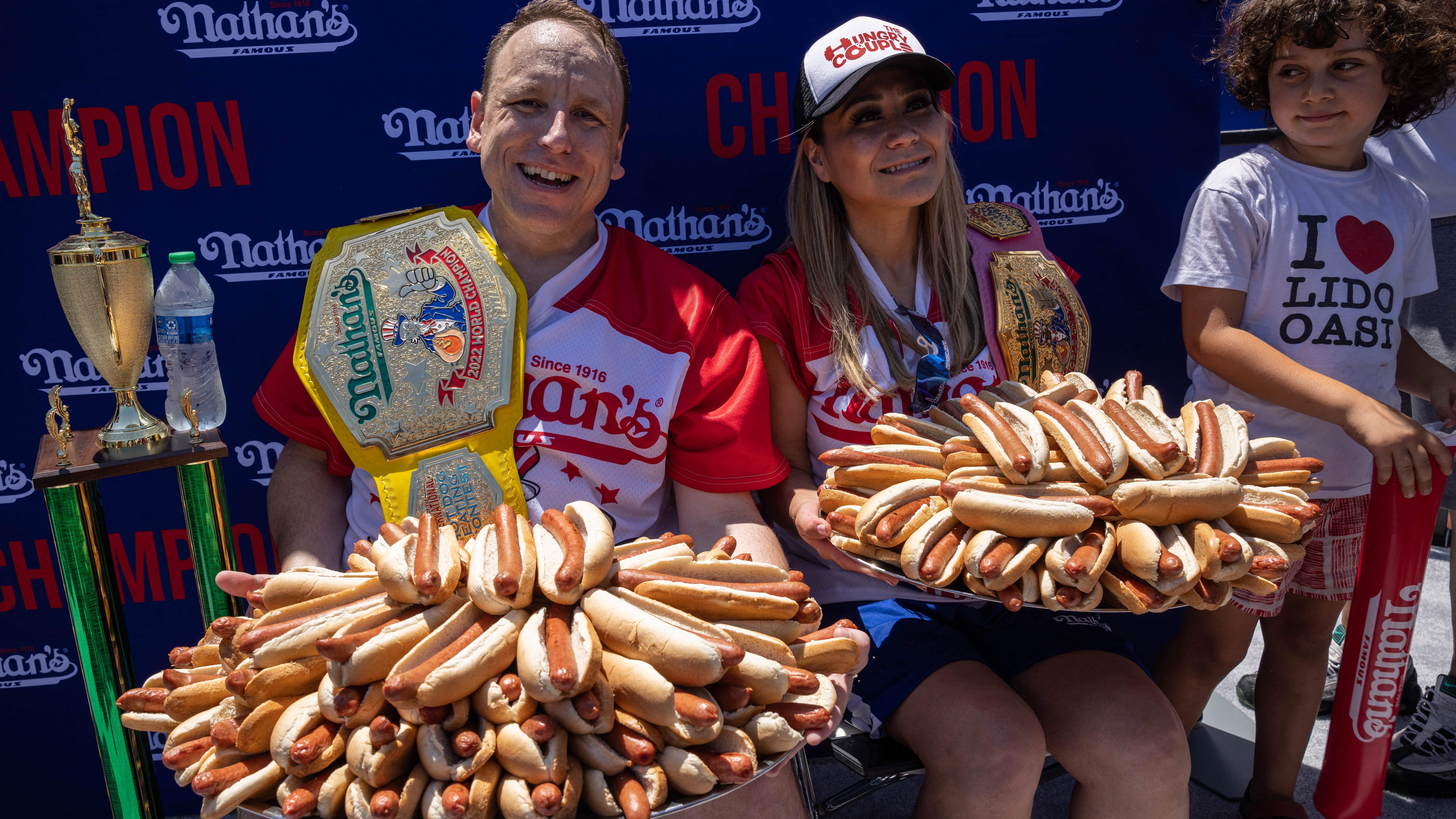 Joey Chestnut (L) and Miki Sudo (R) hold 63 and 40 hot dogs respectively after winning the Nathan&#039;s Famous 4th of July 2022 hot dog eating contest on Coney Island on July 4, 2022 in New York. 