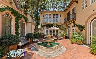 The exteriors of the house with terracotta tiles, a large fountain, lots of plants and creepers along the walls