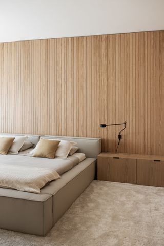 A bedroom with vertical wooden slats on the wall