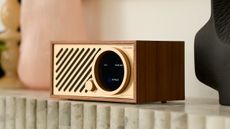 The Tivoli Audio Model One Digital Gen 3 in walnut/gold on top of a stone fireplace or similar decor