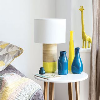bedroom with white walls lamp on table bottle vase with lamp and cushion