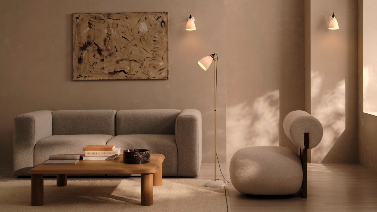 An all beige, modern minimal living room with a light gray sofa and a white modern accent chair. There is a wooden coffee table and art hanging on the wall.