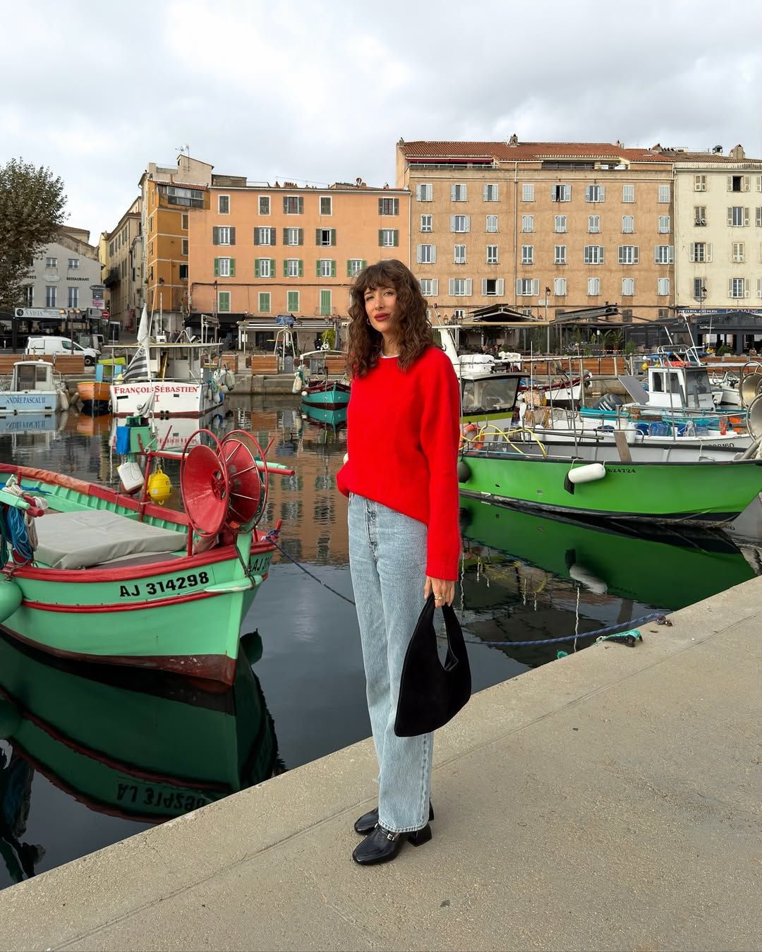 Influencer Julie Sergent Ferreri wearing a red jumper, straight jeans and heeled loafers.