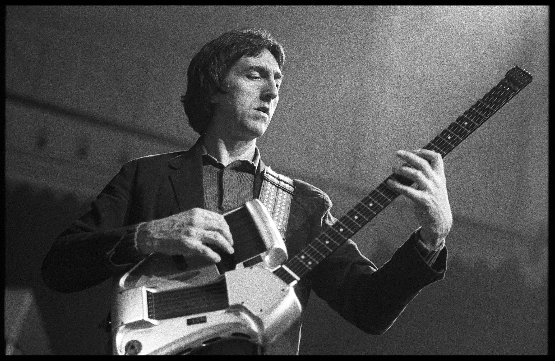 A black-and-white image of Allan Holdsworth performing in 1987 with a SynthAxe