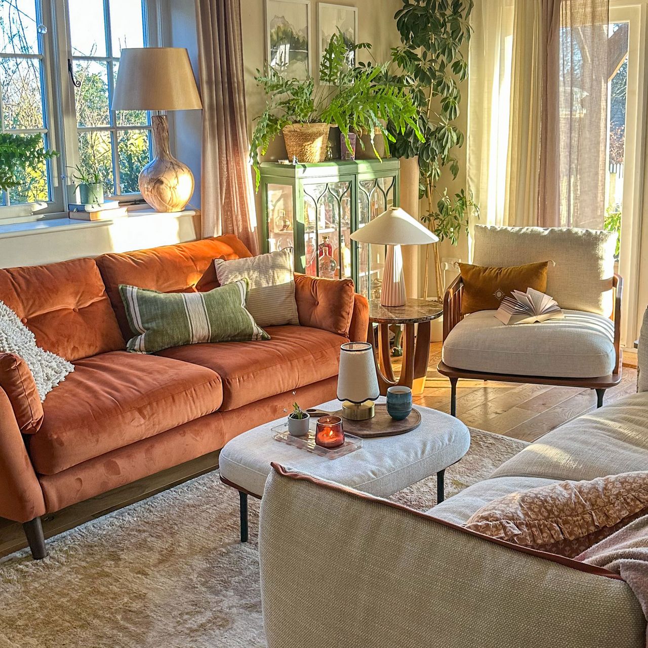 Neutral living room with French doors, orange sofa, glass cabinet and upholstered ottoman