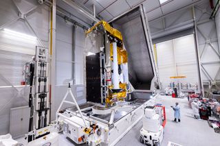 a communications satellite is seen in a clean room in preparation for its launch