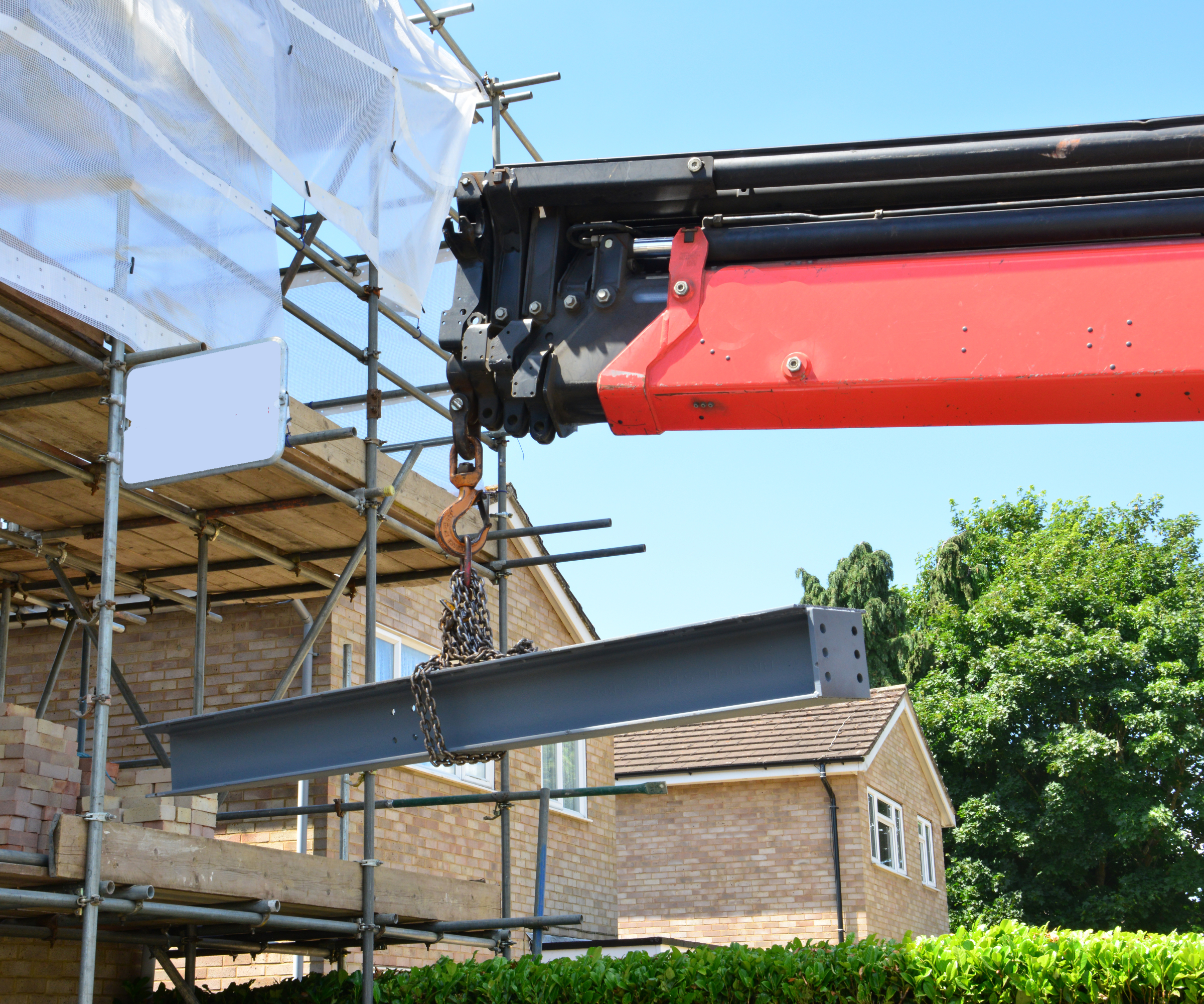 crane lifting steel beam into partly constructed house