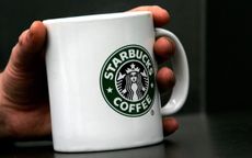 LONDON - APRIL 25:A man holds Starbucks Coffee mug in central London on April 25, 2006 in London, England. The all traditional English style Breakfast 'Fry-Up'is under threat of being replace