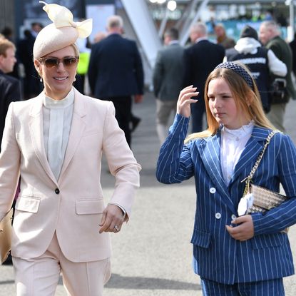 Zara Tindall wearing a pink suit walking next to Mia Tindall in a blue striped suit