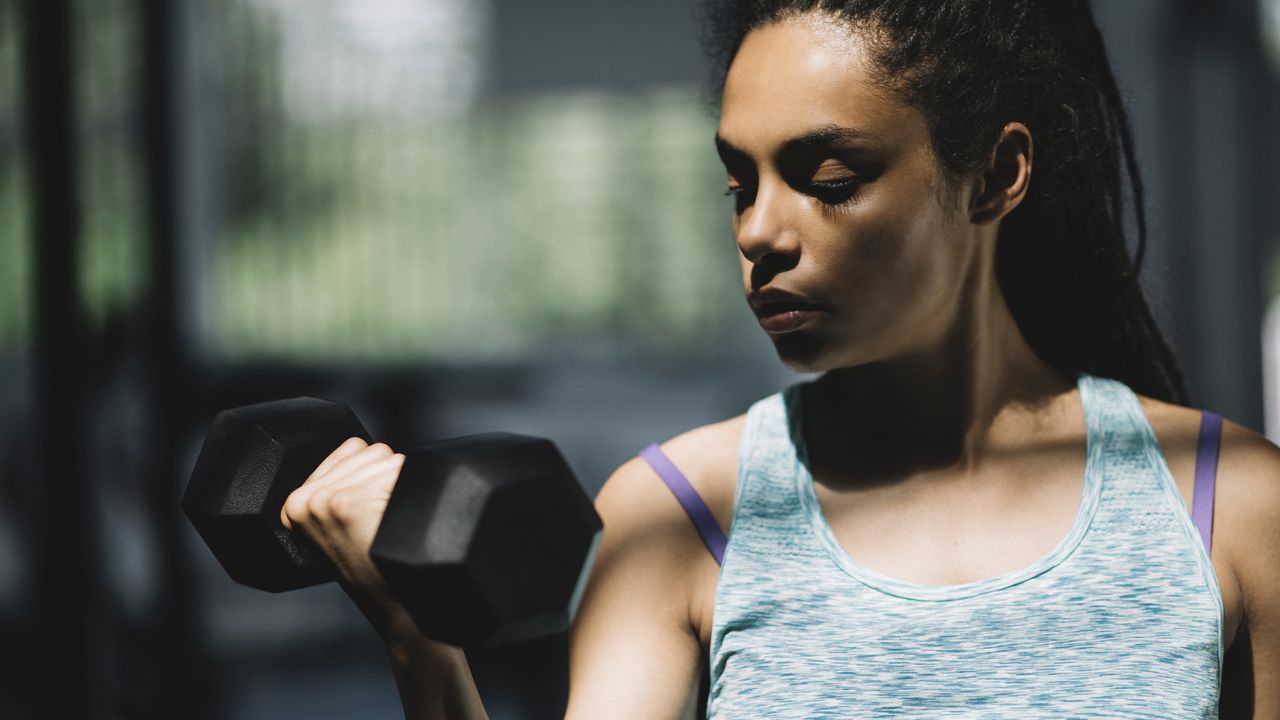 Woman in tank top lifting up a dumbbell