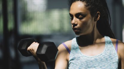Woman in tank top lifting up a dumbbell