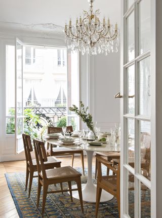 white apartment dining room with chandelier, vintage rug, balcony in foreground