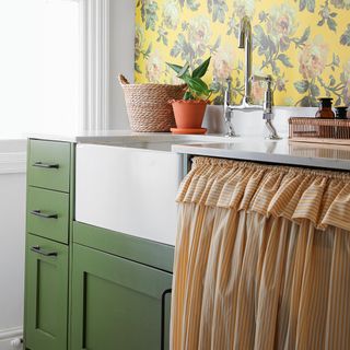 Utility room with green units, Belfast sink and yellow-patterned wallpaper