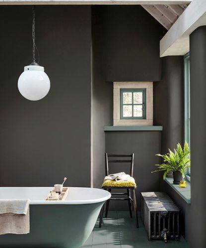 bathroom painted dark gray with blue bath, wooden floors and blue woodwork