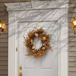 autumn wreath with pumpkins on a white door