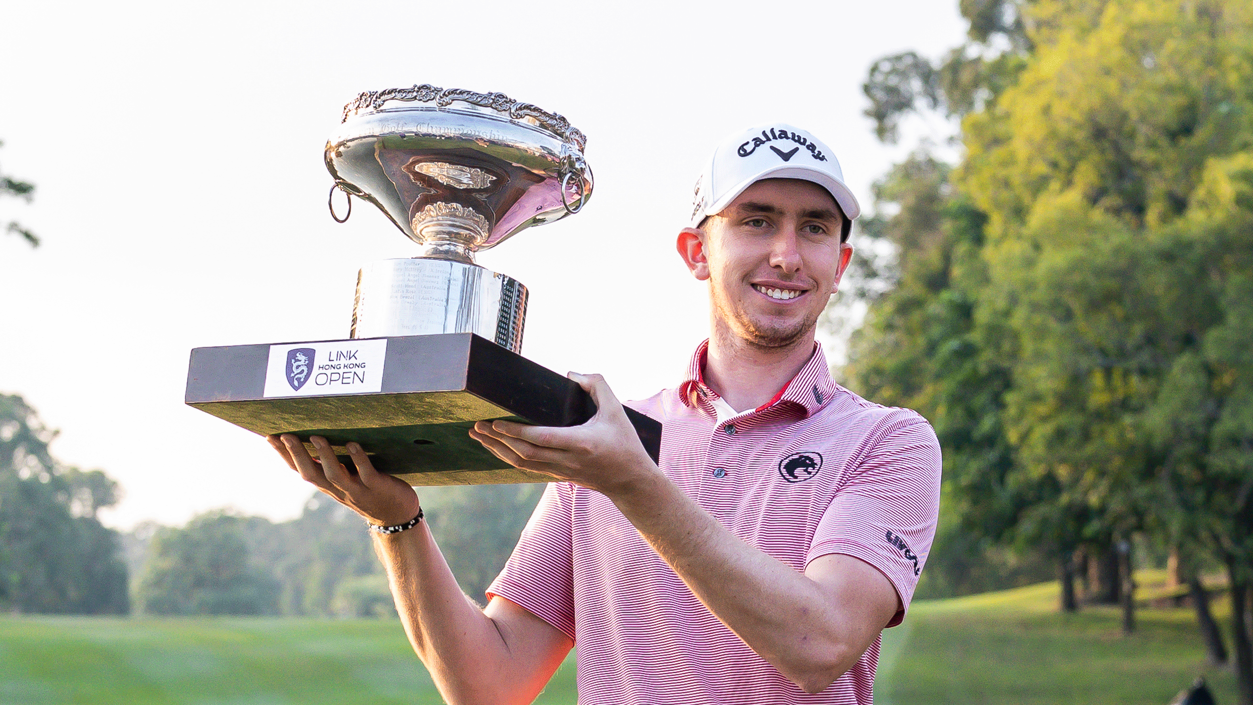 Tom McKibbin holds up the Hong Kong Open trophy while smiling after his win in 2025